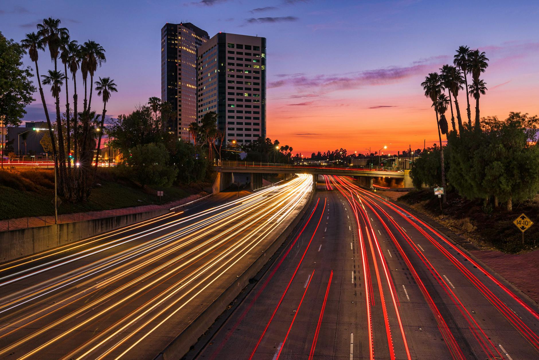 Vibrant sunset view of Burbank highway, palm trees, and light trails creating a dynamic urban scene.