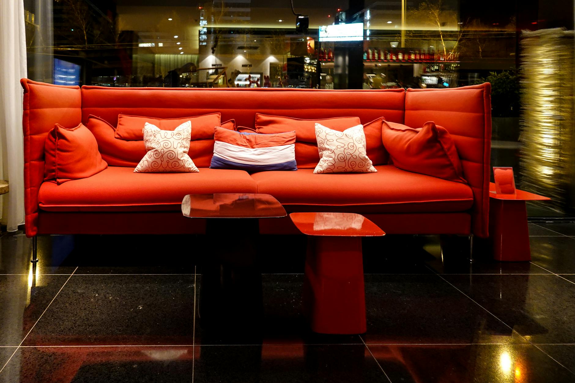 Elegant red sofa with pillows in a stylish nightclub setting, perfect for nightlife ambiance.